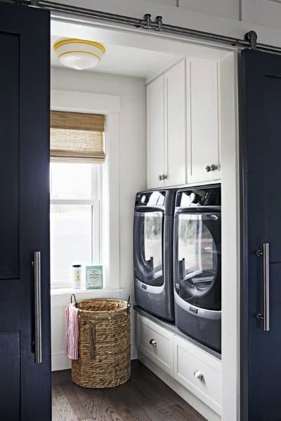 Compact laundry room with white cabinets, dark appliances, sliding doors, and a woven laundry basket.