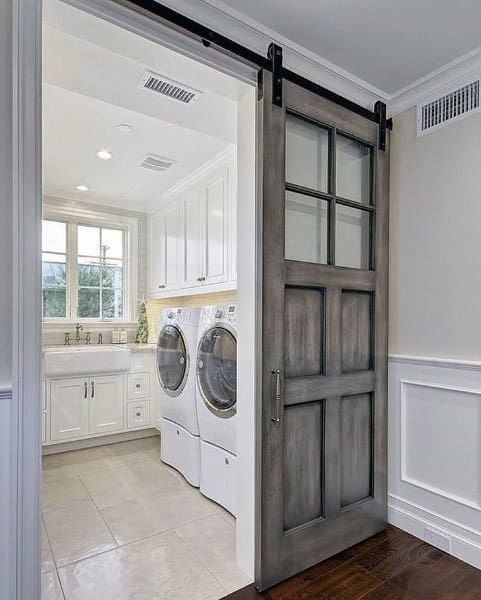 Laundry room with white cabinets, stacked appliances, and a rustic sliding barn door.