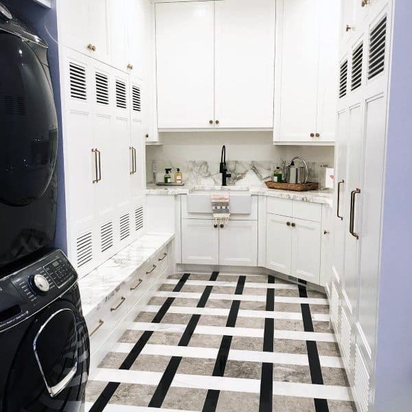 Laundry room with white cabinets, marble countertops, patterned flooring, and stacked appliances.