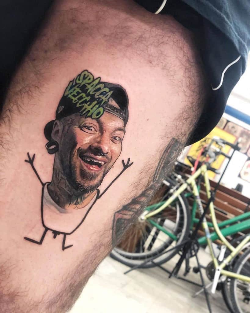 A humorous tattoo featuring a realistic portrait of a man’s face on a simple cartoon stick-figure body, with 'SPACCA VECCHIO' written above.