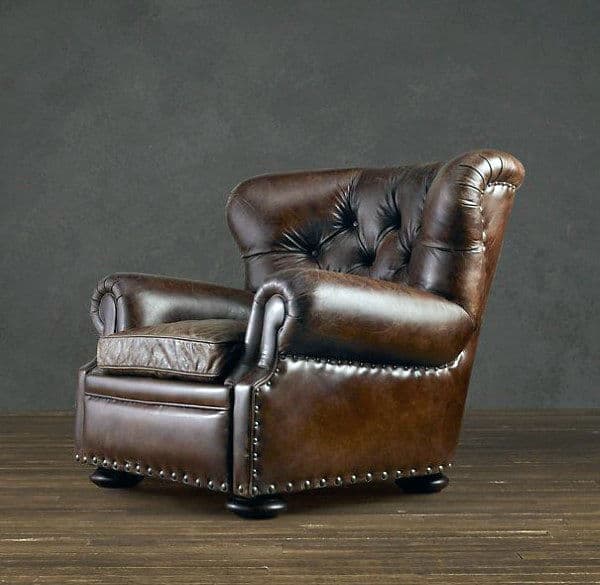 A vintage brown leather armchair with tufted backrest on a wooden floor