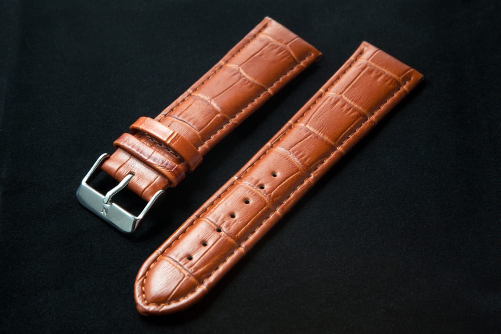 leather watch wrist strap laying on black background