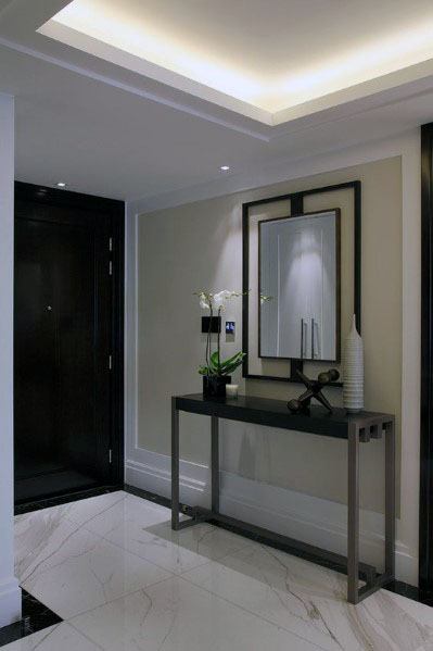 Stylish hallway with LED trey ceiling crown molding lighting, complemented by a modern console table and mirror