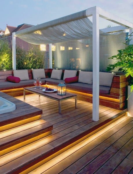 Modern backyard deck with built-in seating, pergola, LED step lighting, and cozy decor.