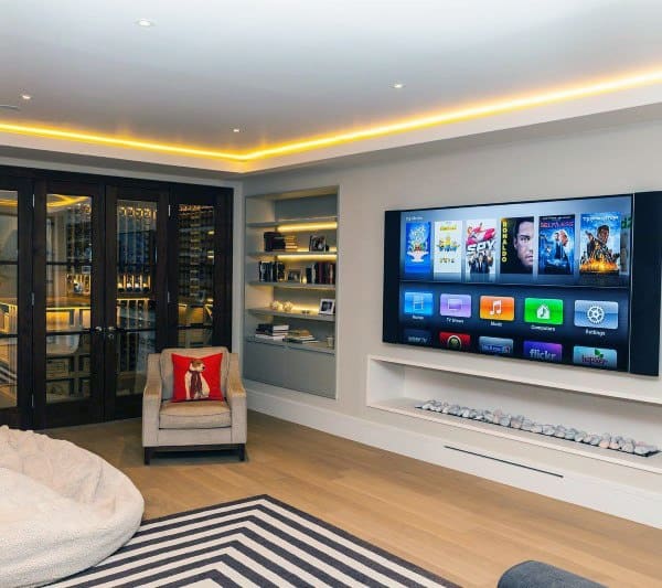Modern basement with LED backlit ceiling, mounted TV, built-in shelves, and glass wine cellar..