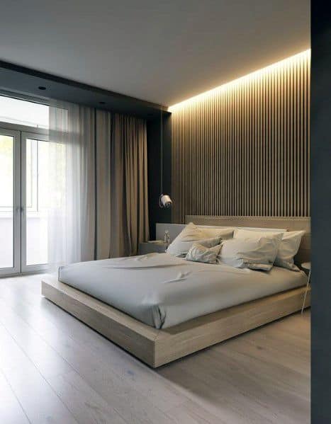 Modern bedroom with wood accent wall, cove lighting, and light vinyl flooring.