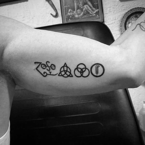 Inner arm tattoo of the four classic Led Zeppelin symbols: Zoso, triquetra, Borromean rings, and feather in a circle.