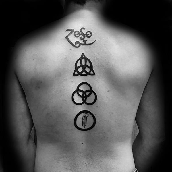 Vertical back tattoo of Led Zeppelin’s four symbols—Zoso, triquetra, Borromean rings, and feather—centered along the spine.