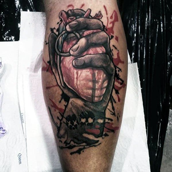 Realistic tattoo of a hand gripping a heart-shaped grenade with blood splatter details, inspired by Green Day’s *American Idiot* cover art.