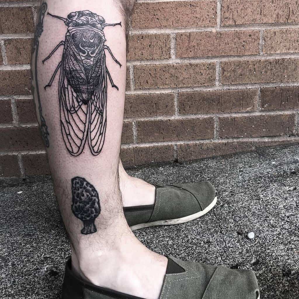 Leg with tattoos of a cicada and a mushroom