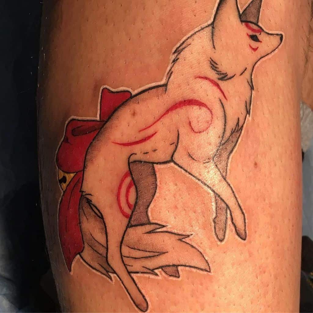 Leg tattoo of a Japanese wolf with red markings, curled tail, and a red bow tied around its back
