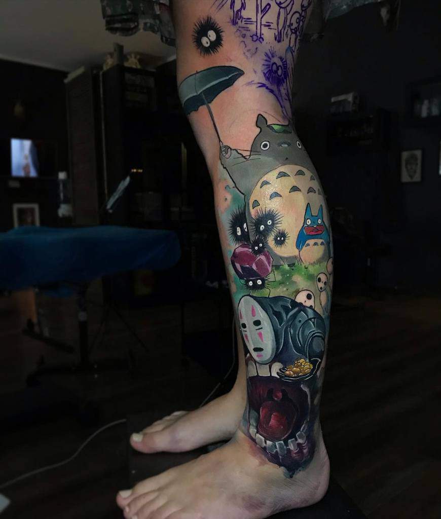 Intricate leg sleeve tattoo featuring Totoro with an umbrella, soot sprites, No-Face, and other Studio Ghibli characters in a vibrant, detailed composition