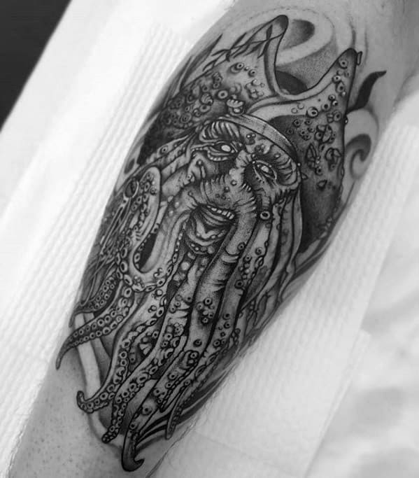 Black and white tattoo of a bearded, tentacled pirate face like Davy Jones on an arm