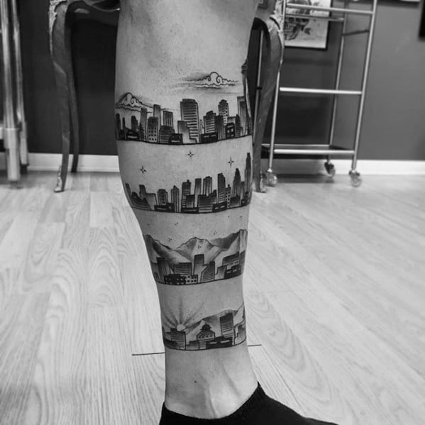 Leg tattoo featuring four horizontal bands of Los Angeles skyline scenes, including city buildings, stars, and mountains in black ink.
