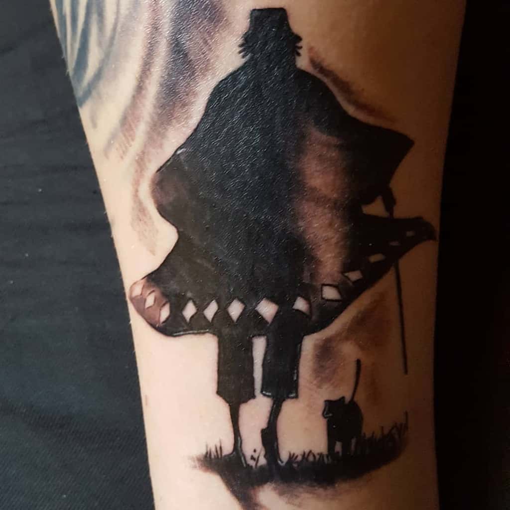 Black ink silhouette tattoo of Kisuke Urahara from Bleach, featuring his iconic hat, cloak, and cane, with Yoruichi in cat form beside him