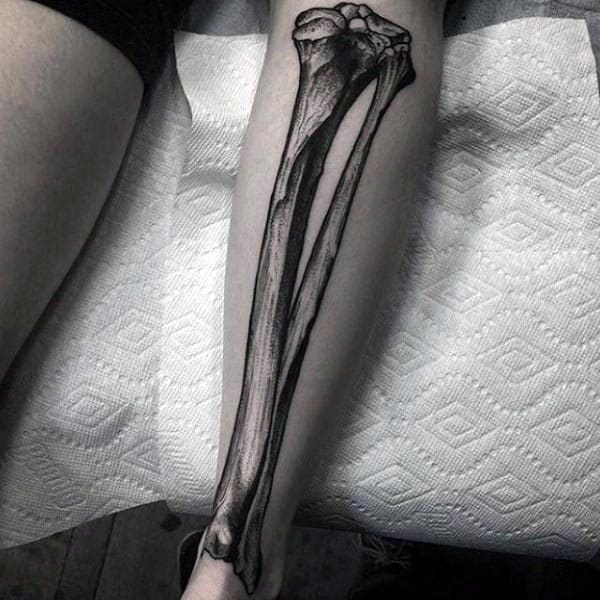 Realistic black and grey tattoo of forearm bones, the radius and ulna, placed anatomically along the length of the lower arm.
