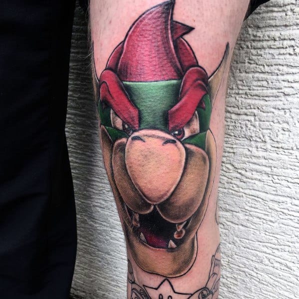 Bold Bowser tattoo on a man's leg featuring a fierce expression, rich shading, and dynamic details for a striking and intense Mario-inspired design.