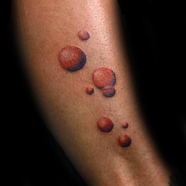 Tattoo of several red-toned bubbles arranged in a flowing pattern, with soft shading and highlights for a realistic, three-dimensional effect.