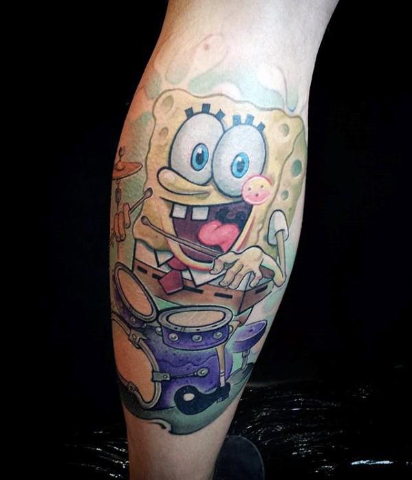 Colorful SpongeBob tattoo on calf showing him drumming with excitement, tongue out, and candy in hand behind a purple drum set.