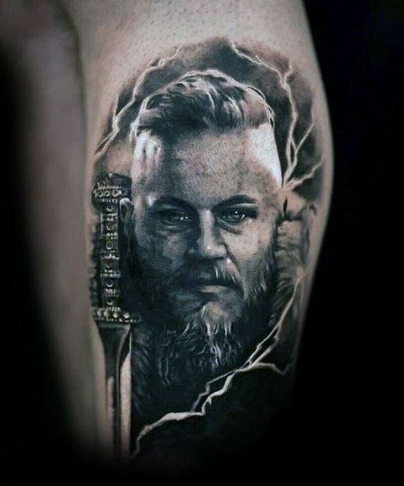 A detailed tattoo of a Ragnar holding a sword on his arm, surrounded by lightning