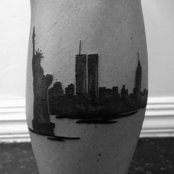Solid black silhouette tattoo of the New York City skyline featuring the Statue of Liberty, Twin Towers, and surrounding buildings.