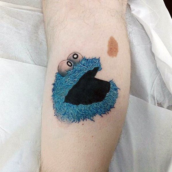 Simple Cookie Monster tattoo with fluffy blue fur and googly eyes, gazing upward toward a nearby birthmark resembling a cookie.