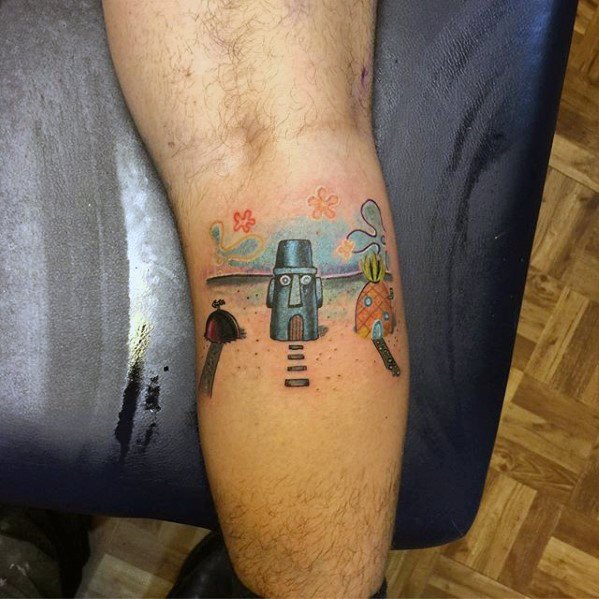 Tattoo of Bikini Bottom street scene on the leg featuring SpongeBob’s pineapple house, Squidward’s tiki home, and Patrick’s rock.