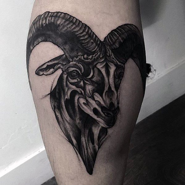 Tattoo of a ram's head with large horns on lower leg back part