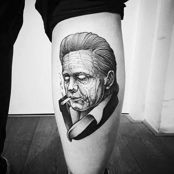 Tattoo of Johnny Cash with slicked-back hair and a cigarette on someone's leg