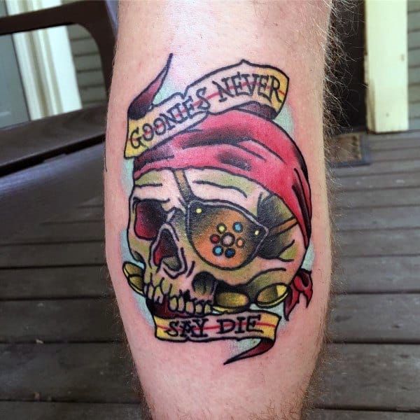 Colorful tattoo of One-Eyed Willy from The Goonies, featuring a skull with a red bandana, gold teeth, and a banner reading "Goonies Never Say Die".