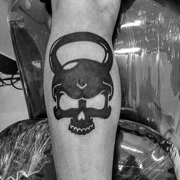 Bold black kettlebell skull tattoo on the calf, symbolizing strength, endurance, and a fearless dedication to fitness and CrossFit training.