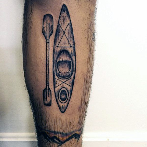 Alt text: Black and grey tattoo of a kayak and paddle, featuring detailed lines and shading for a minimalist yet striking design.