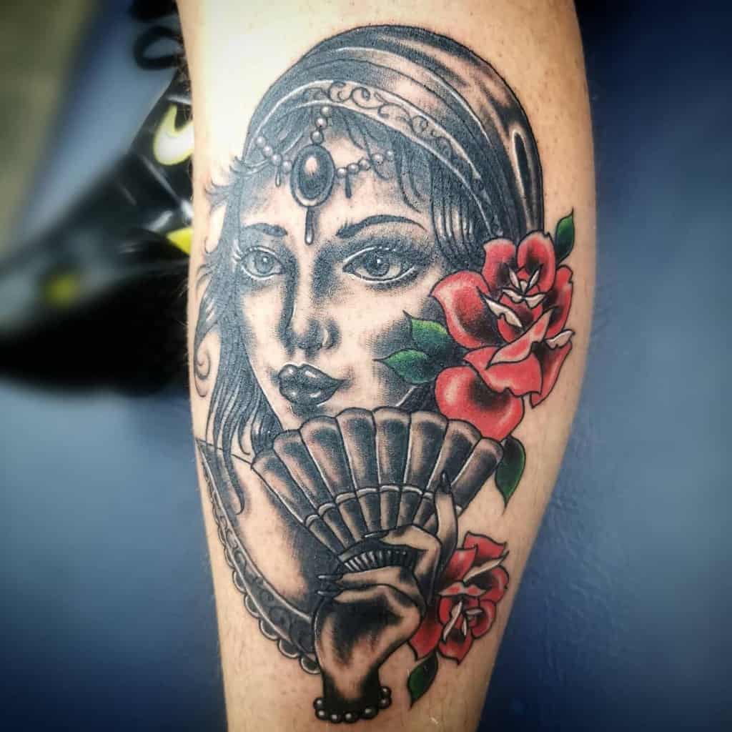 Tattoo of a gypsy woman with a fan and red roses on an arm