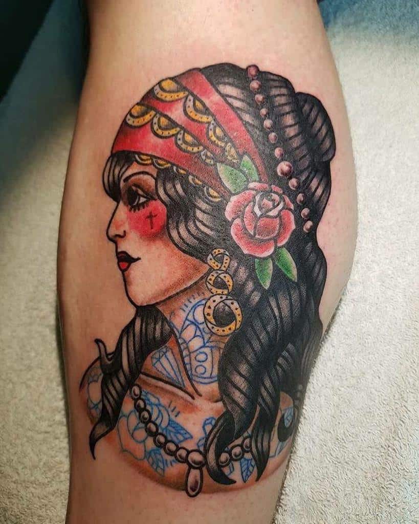 A traditional tattoo of a gypsy woman adorned with a red bandana, rose, and flowing long hair