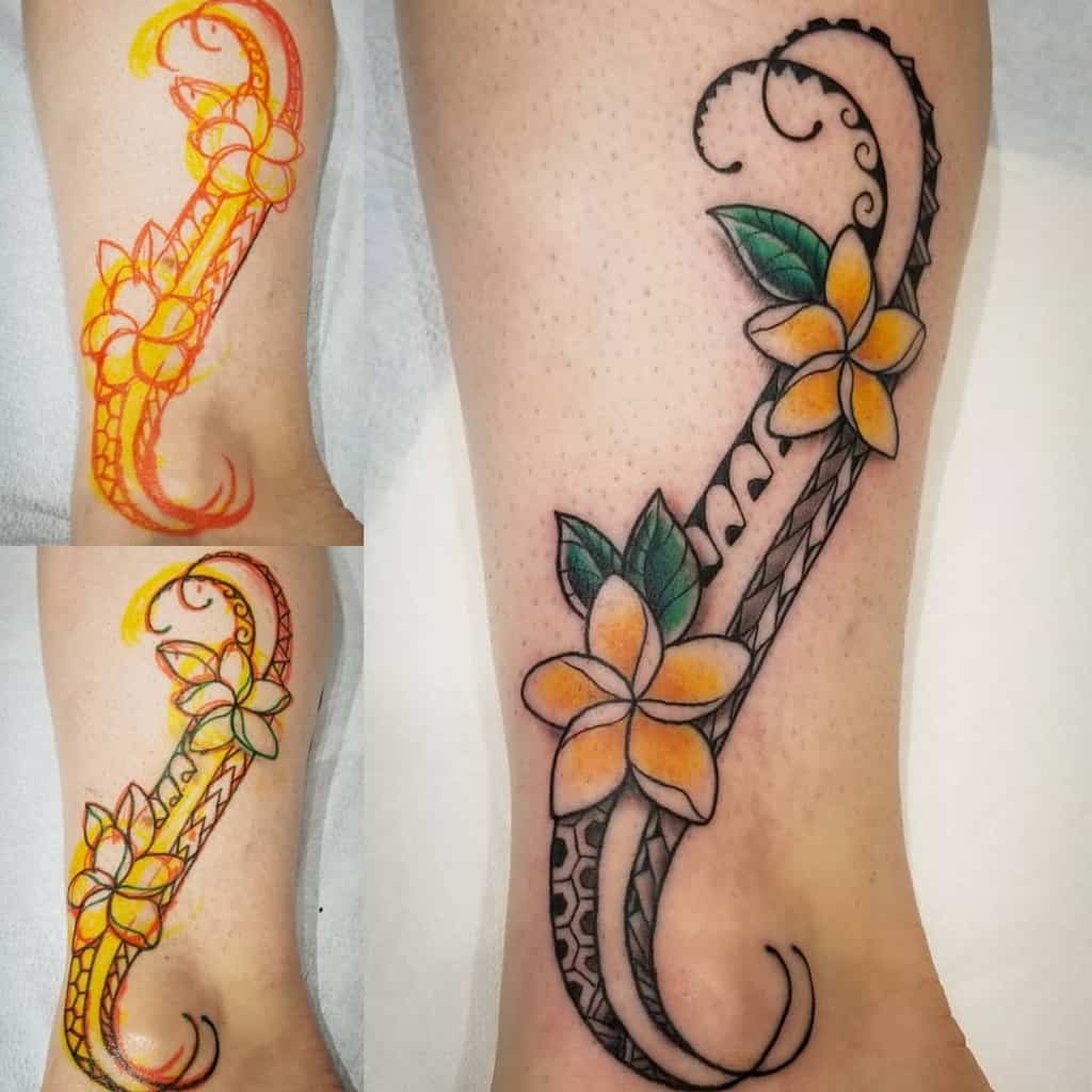 Leg tattoo featuring yellow plumeria flowers with green leaves and intricate black tribal swirls on the side.