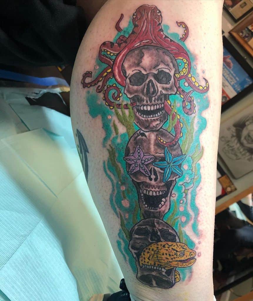 Colorful tattoo on a leg featuring three skulls stacked vertically, adorned with underwater elements such as an octopus, starfish, and eel, symbolizing 'Hear No Evil, See No Evil, Speak No Evil'