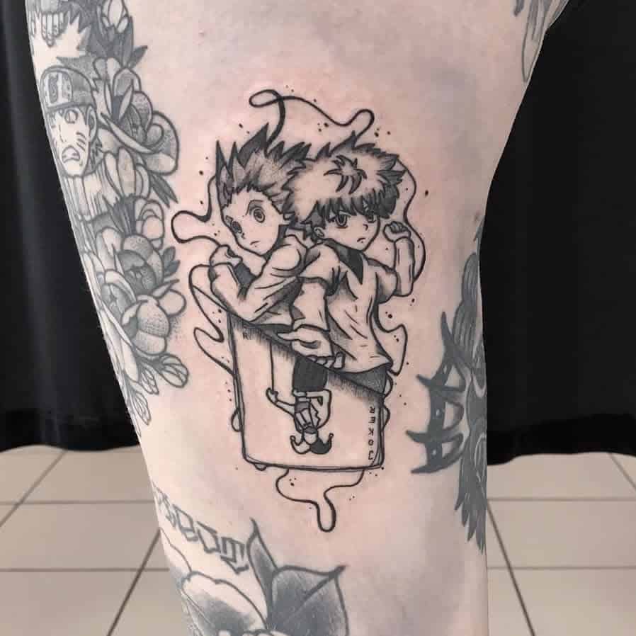 Black and white tattoo of Gon and Killua from Hunter X Hunter sitting back-to-back on a thigh