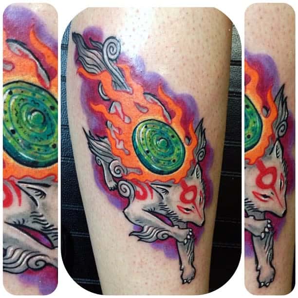 A tattoo of a mythical Japanese creature, resembling a fierce wolf, adorned with flames and a green disc on its back, elegantly wraps around the leg