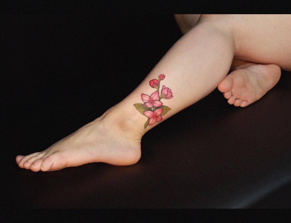 Leg with a floral tattoo featuring pink flowers and green