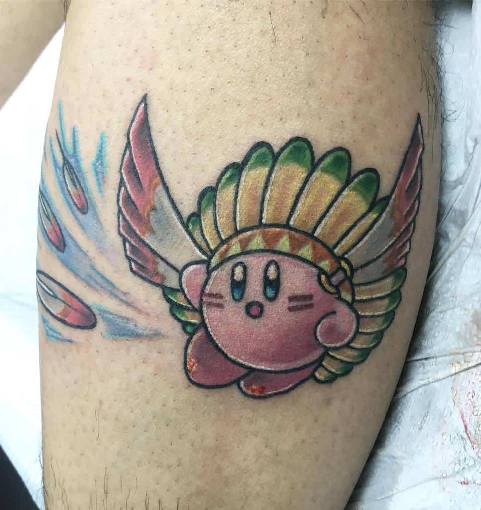 Kirby tattoo with a feathered headdress, strip lines on his face and large wings, soaring with a trail of energy