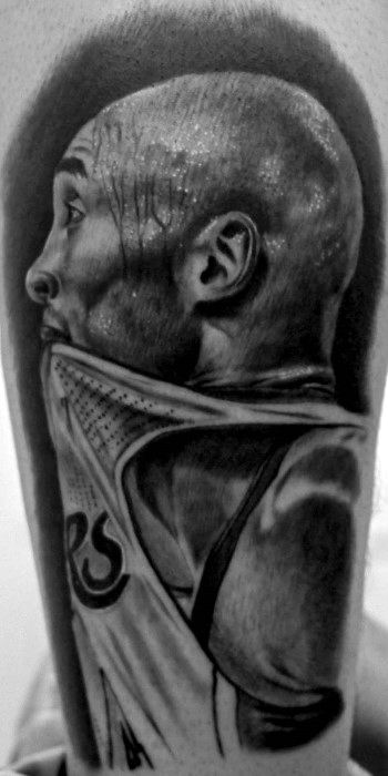 A black and white tattoo of Kobe Bryant pulling his Lakers jersey over his head, captured in detailed shading, showcasing his intense expression.