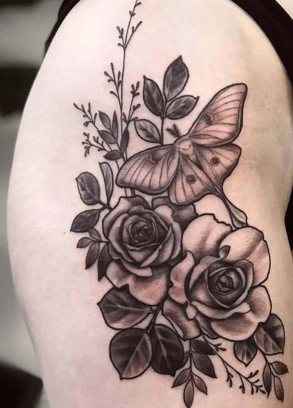A black and grey tattoo featuring a Luna Moth surrounded by detailed roses and foliage