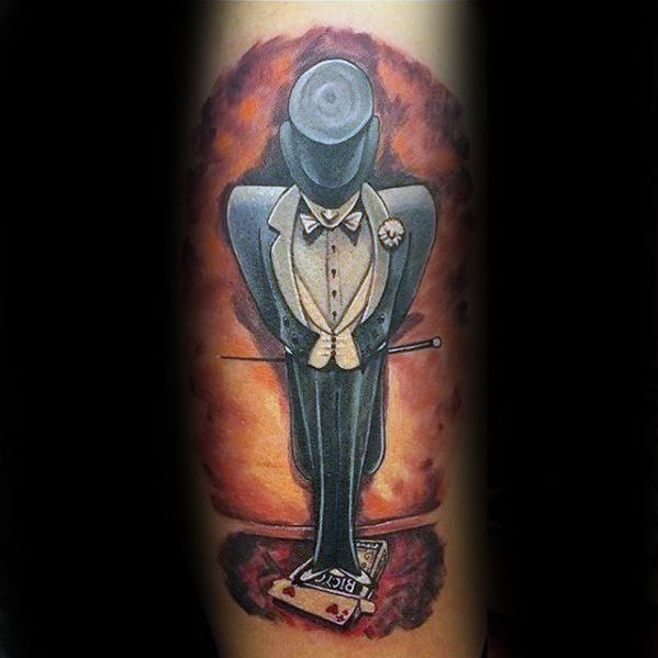 Tattoo of a magician in a suit and top hat standing on deck of playing cards