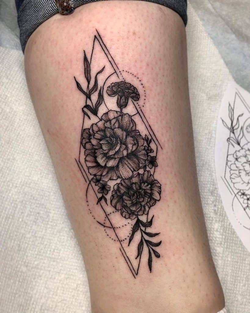 Beautiful black and grey marigold tattoo with geometric framing and delicate shading, offering a bold yet elegant design on the leg
