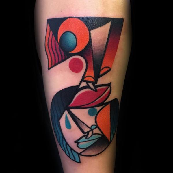 Cubist tattoo on the forearm featuring an abstract face with bold red, teal, and orange shapes, geometric accents, and teardrop details.