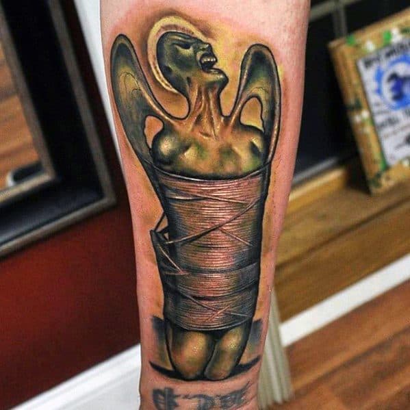 Colorful forearm tattoo of the eerie angel figure wrapped in bandages from Metallica’s Load album cover art.