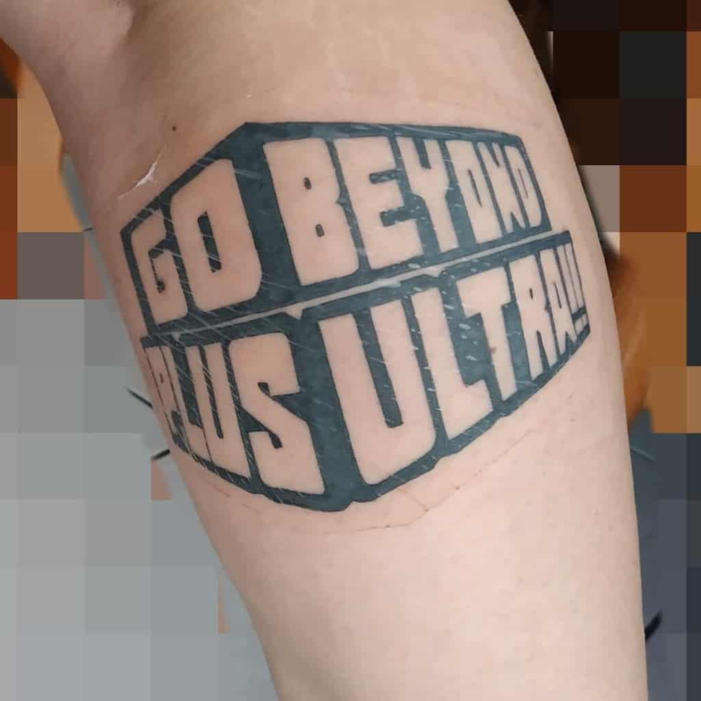 Bold black and grey tattoo of 'Go Beyond Plus Ultra!!!' in blocky, three-dimensional lettering, inspired by My Hero Academia's motto