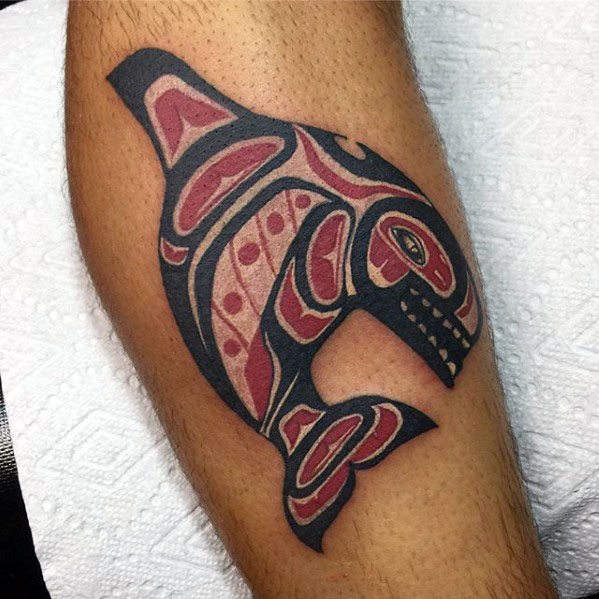 Bold tribal-style orca tattoo on the forearm, featuring intricate patterns in black and red, symbolizing strength and movement with sharp, angular lines.
