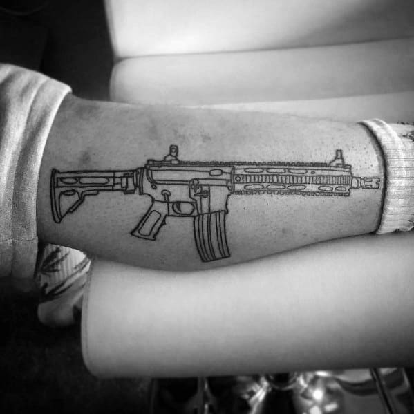 Minimalist black outline AR-15 tattoo on the thigh, featuring clean lines and a tactical design, symbolizing precision, strength, and firearm appreciation.