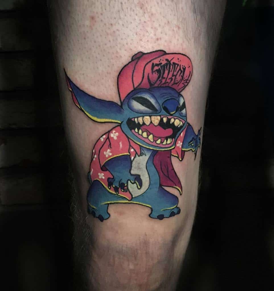 Colorful tattoo of Stitch from Lilo & Stitch wearing a red cap and floral shirt, striking a playful pose, on the lower leg.
